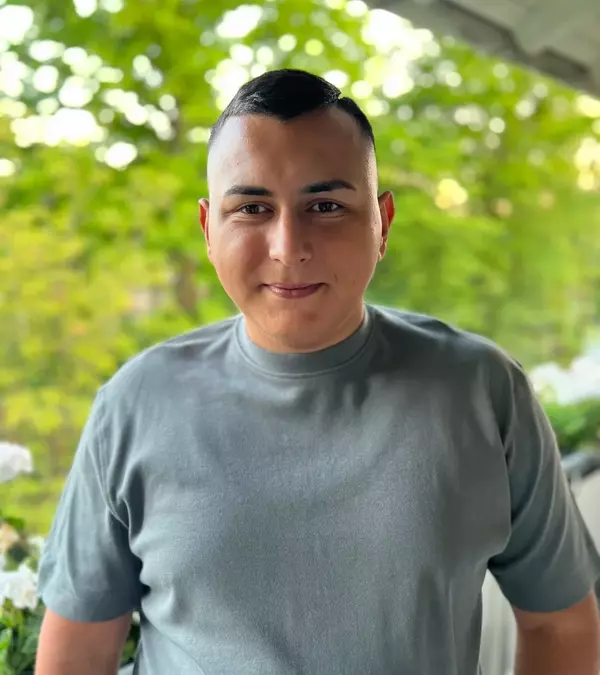 Männlich gelesene Person mit dunklem Bart, freundlich lächelnd